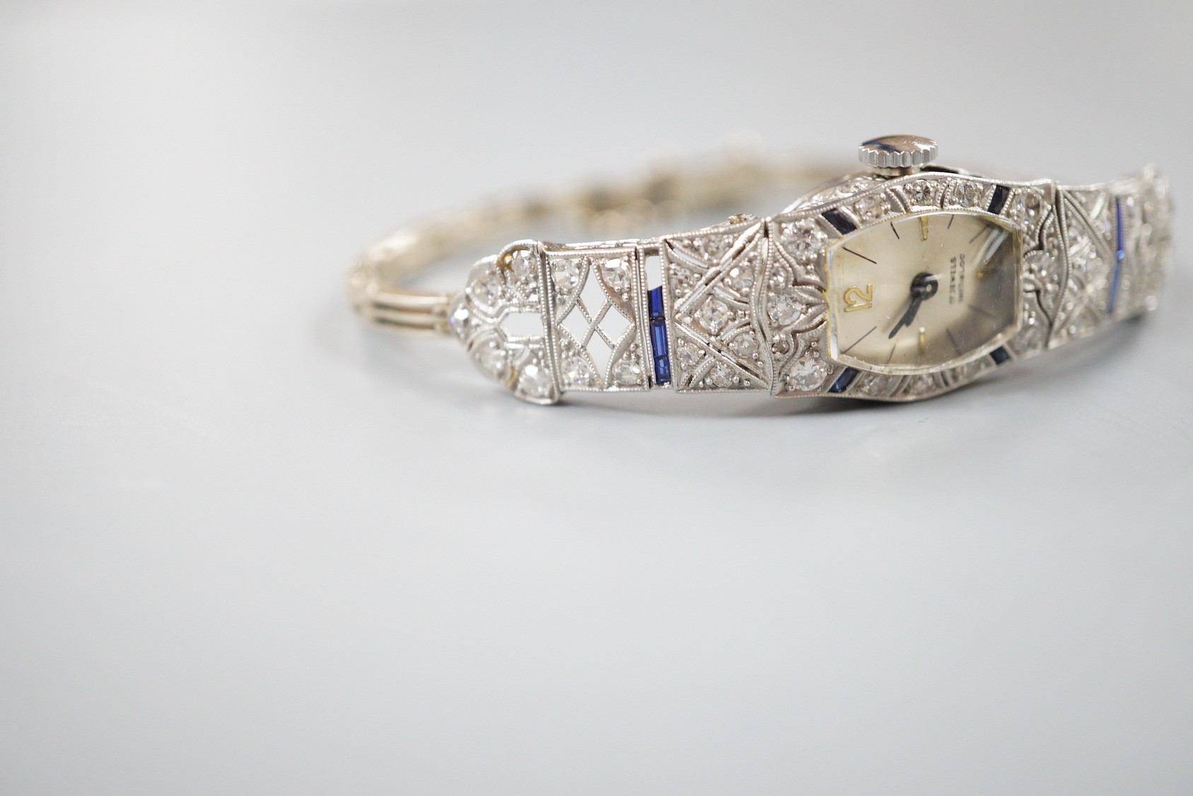 A lady's mid 20th century white metal, sapphire and diamond cluster set cocktail watch, on a 9ct bracelet (a.f.), gross weight 17.2 grams.